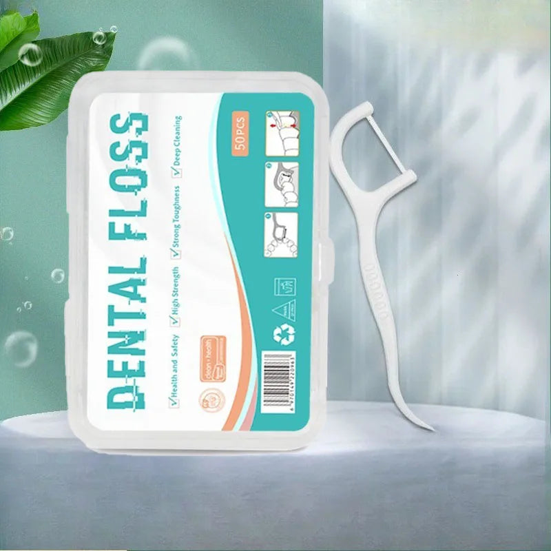 A white container of dental flossers with a green and teal label and a white plastic tool is displayed on a light surface.