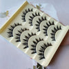 A plastic tray holding five pairs of long and thick black false eyelashes for eye makeup.
