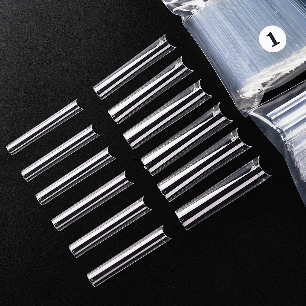 A set of acrylic false press-on nails in various lengths and shapes is displayed on a black surface.