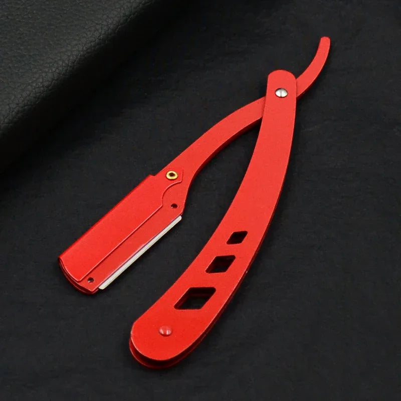 Un couteau de rasage antique rouge à pliage avec une lame et une poignée courbées sur fond noir.