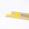 A bamboo toothbrush with soft yellow bristles and a yellow label indicating 100% biodegradable.