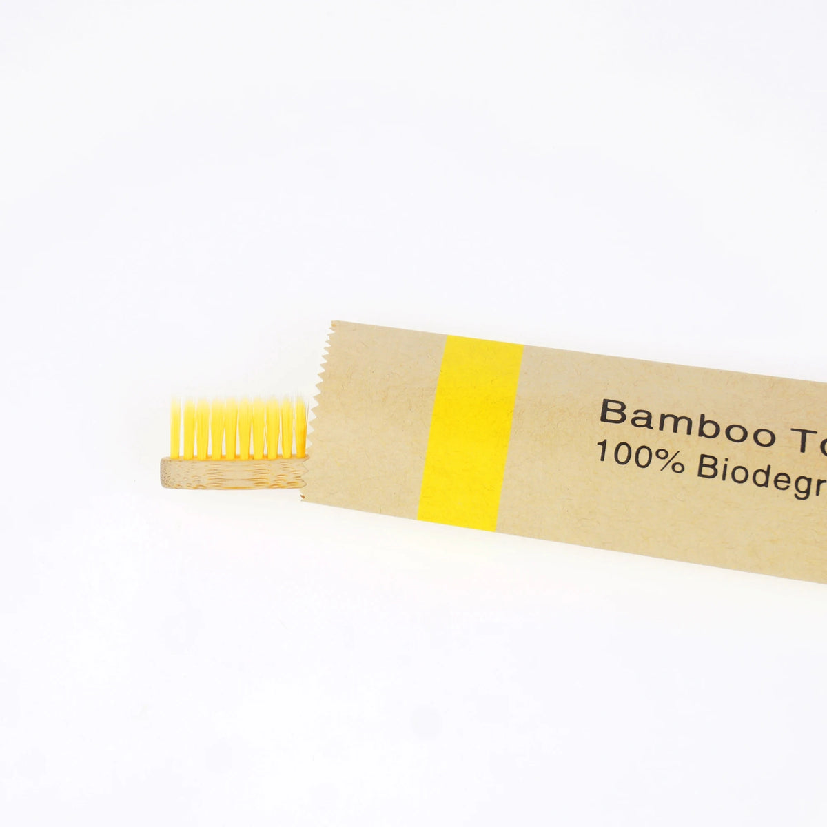 A bamboo toothbrush with soft yellow bristles and a yellow label indicating 100% biodegradable.