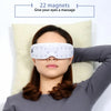 Eine Frau benutzt ein weißes magnetisches Augenmassiergerät, um ihren Augen eine Massage zu geben.