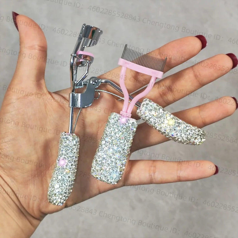 A hand holds a professional eyelash curler set with metal and pink plastic components.