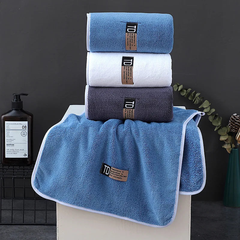 A stack of four blue and white microfiber cleaning towels with brown labels displayed on a white surface.
