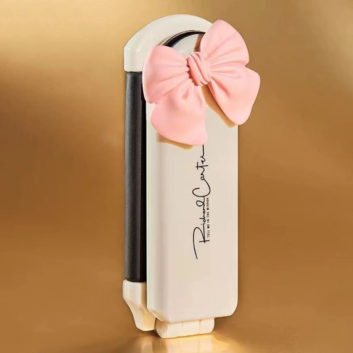 A white folding pocket hair comb with a pink bow and mirror is shown against a warm brown background.