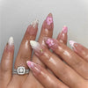 A hand displays a set of 24-piece almond press-on nails featuring pink and white floral and butterfly designs.