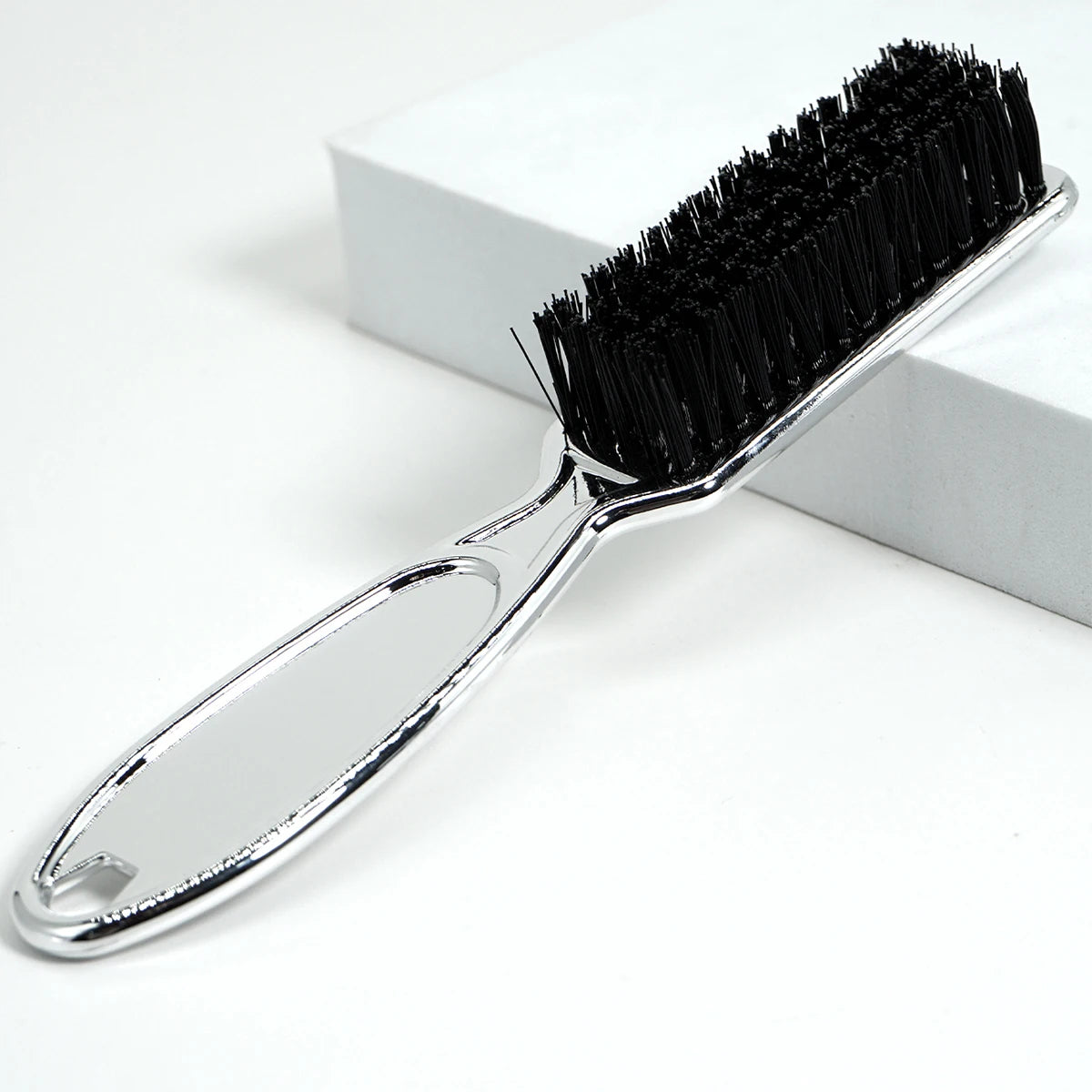 A silver brush with black bristles used for professional neck and facial hair cleaning.