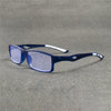 Un par de gafas deportivas azules oscuras anti-luz descansando sobre una superficie gris texturizada.