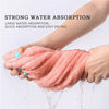 A hand is holding a pink microfiber hair towel wrap, demonstrating strong water absorption and quick drying.