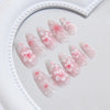 A collection of 24 press-on nails featuring a sheer pink base with delicate pink flowers.