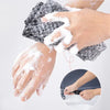 A hand is using an exfoliating back scrubber bath towel to cleanse the skin.