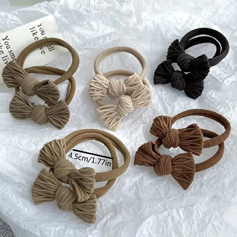 Colección de diez gomas para el pelo de trenzas de tejido beige y negro, mostradas en papel blanco.