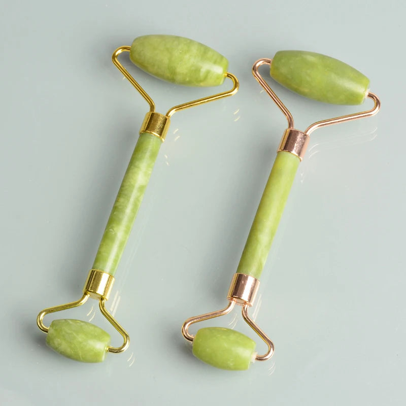 A pair of jade gua sha facial massagers with gold-toned handles and light green stones.