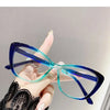 A hand holds a pair of blue-tinted cat eye reading glasses against a light background.