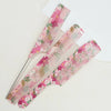 A set of two pink floral dual hair combs lying on a white surface.