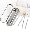 Stainless steel U-shaped tongue scraper and cleaning brush set resting on a white towel.