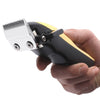 A hand holds a black and gold professional LCD hair clipper set with a silver comb attachment.