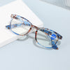 Pair of blue and brown patterned magnifying reading glasses resting on a white surface.