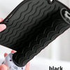 A black silicone heat resistant mat for hair styling tools is being held by a hand.