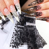 Gros plan de ongles manucurés avec des décalcomanies en feuille de dentelle noire et blanche.