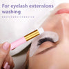 A hand is using an eyelash extension cleaning brush on a model's eye for washing.
