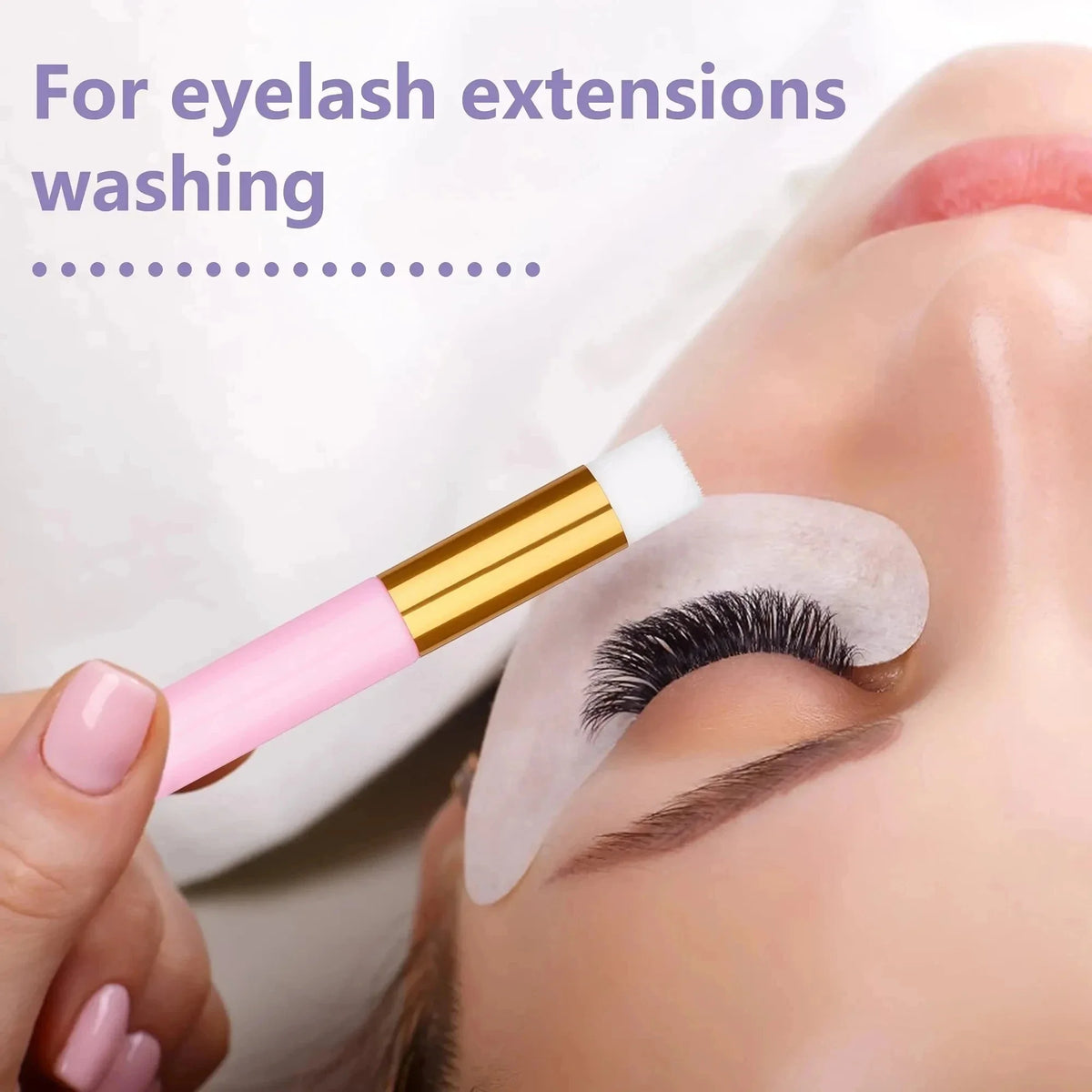 A hand is using an eyelash extension cleaning brush on a model's eye for washing.