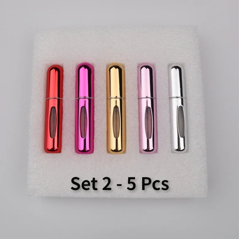 A set of five colorful mini perfume spray bottles in various metallic shades arranged on a white foam pad.