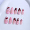 A set of press-on nails featuring a pink base with a plaid pattern and small flower accents.