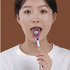 A woman holds a purple silicone tongue scraper near her mouth.