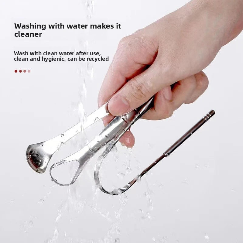 A hand is washing a stainless steel U-shaped tongue scraper under running water.
