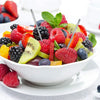 Un bol de fruits frais comme des fraises, framboises, bleuets, kiwi et segments d'agrumes, garni de feuilles de menthe