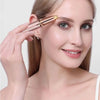 A woman is using a gold-toned electric eyebrow trimmer on her upper eyelid.