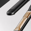 A black ceramic hair straightener is shown with a drop of liquid coating on the barrel.
