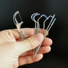 A hand holds several reusable metal toothpicks for deep oral cleaning.