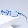Un par de gafas de lectura con marco azul y lente estampada sobre una superficie blanca.