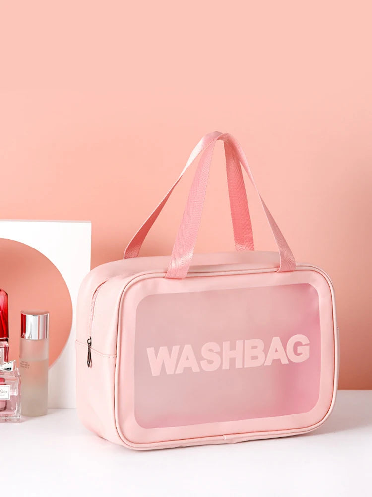 A pink transparent cosmetic storage bag with pink straps is displayed against a light pink background.