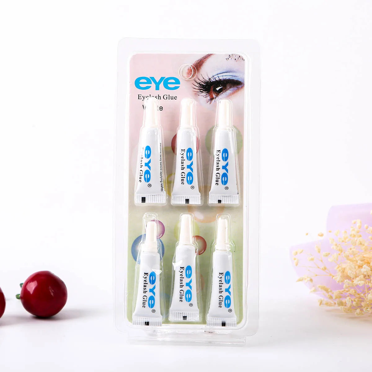 A clear plastic container holding three tubes of EYE eyelash glue for false lashes.