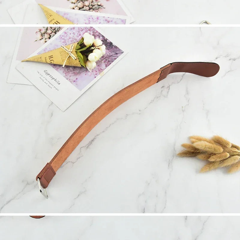 A brown leather sharpening strop is shown next to a pink and purple card with floral accents.