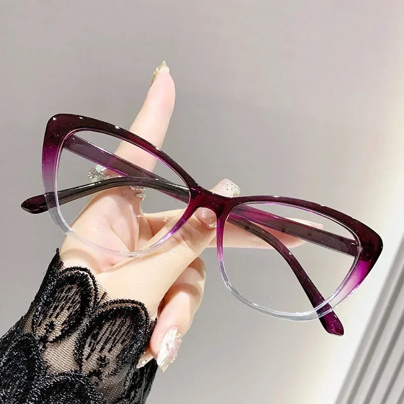 Purple cat eye reading glasses being held by a hand with black lace sleeve