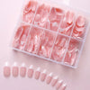 A clear plastic box filled with nude pink matte French press on nails displayed on a light pink surface.