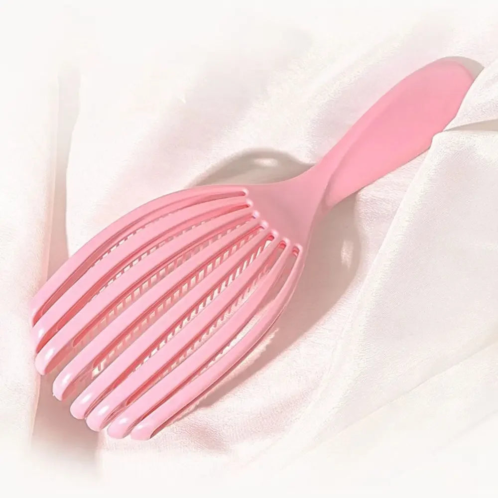 A pink massage detangler hair brush is shown against a white satin background.