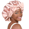 Una mujer modela un gorro de pelo de satén rosa de doble capa atado en un gran lazo.