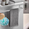 A silver bathroom shelf holds a natural dry brushing body scrub brush, a gray towel, and a blue floral sponge.