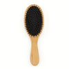 A natural boar bristle hair brush with a light wood bamboo handle.
