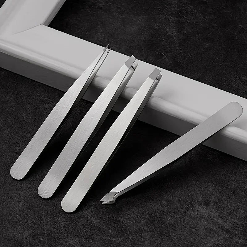 A set of professional stainless steel tweezers lying on a dark surface next to a white frame.