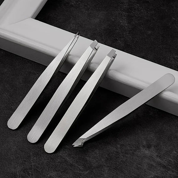 A set of professional stainless steel tweezers lying on a dark surface next to a white frame.
