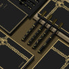 A set of black toothbrushes with gold accents displayed on dark brown and black packaging.
