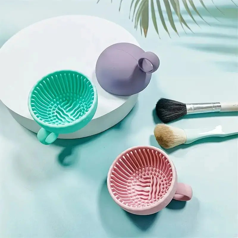 A set of silicone makeup brushes and a purple brush cleaner are displayed on a light blue surface.