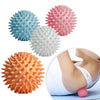 A collection of pink, blue, white, and orange deep tissue massage balls shown next to a hand applying one on a foot.